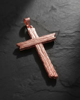 Rose gold finish cross pendant with wood grain texture showing warm metallic tones and crafted surface detail