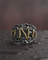 Close-up of Frankenstein ring displaying intricate golden wire stitching pattern on weathered silver surface