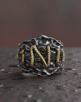 925 sterling silver Frankenstein ring with golden rope stitching details on textured dark surface background