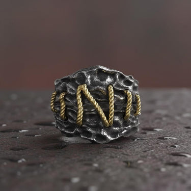 925 sterling silver Frankenstein ring with golden rope stitching details on textured dark surface background