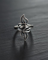 Oxidized Silver Leaf Ring with an intricate openwork design of four leaves, resting on a dark, textured slate surface.