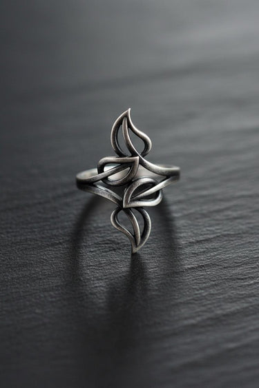 Oxidized Silver Leaf Ring with an intricate openwork design of four leaves, resting on a dark, textured slate surface.