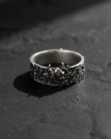 Oxidized sterling silver Hannya mask ring showing the detailed demonic face and horns on a dark slate background.