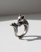Handcrafted silver cat ring with an oxidized finish, showing the cat's face and paws resting on its tail.