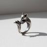 Handcrafted silver cat ring with an oxidized finish, showing the cat's face and paws resting on its tail.
