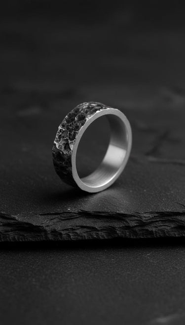 Oxidized Moon Surface Silver Ring shown at an angle on a dark slate surface, highlighting the deep texture and smooth interior.