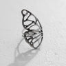Silver butterfly wing ring with a delicate openwork design, resting on a white textured surface showing its fine craftsmanship.