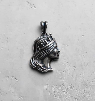Silver Queen Pendant with an oxidized finish showing detailed hair texture, viewed from a slight angle on a gray surface.