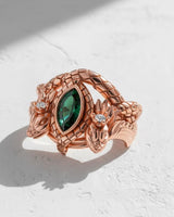 Artisan rose gold vermeil dragon ring with intricate scale details and a vibrant emerald, displayed on a clean white background.