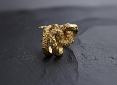 Angled side view of the sterling silver snake ring on a dark surface, showcasing the layered coils that form the band.