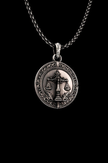 Angled close-up of the silver Scales of Justice pendant, highlighting the oxidized finish and intricate details of the central scales emblem.
