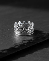 Side view of the handcrafted silver crown ring, highlighting the intricate regal band design on a dark slate background.