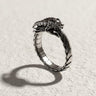 Silver Ouroboros dragon ring with detailed scales on a textured white surface, showing the intricate head design biting its tail.