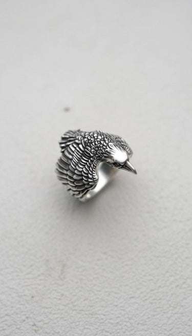 Top-down view of the Silver Raven Ring showcasing the full spread of its intricately carved wings and plumage on a plain background.