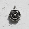 Oxidized 925 silver Tudor Rose Pendant showing detailed layered petals and thorns, casting a shadow on a white wall.