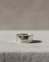 Minimalist 925 sterling silver piston ring with engine groove details displayed on textured grey surface