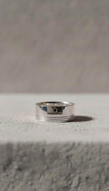 Minimalist 925 sterling silver piston ring with engine groove details displayed on textured grey surface