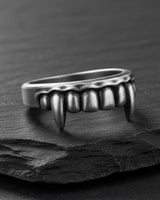 Silver Vampire Fangs Ring with an oxidized finish, showcasing the detailed teeth and sharp canines on a dark slate surface.