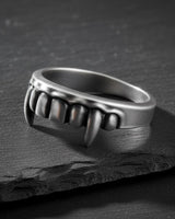 Unisex 925 sterling silver Vampire Fangs Ring, a gothic statement piece, resting on a textured black rock background.