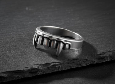 Unisex 925 sterling silver Vampire Fangs Ring, a gothic statement piece, resting on a textured black rock background.
