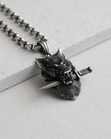 Front view of the handcrafted silver wolf pendant with a knife, highlighting the fierce expression and intricate fur texture.
