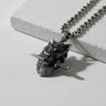 Oxidized 925 sterling silver wolf pendant shown at an angle, detailing the wolf clenching a dagger in its teeth.
