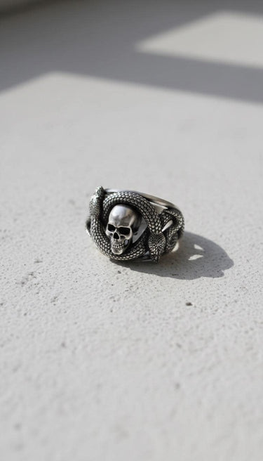 Angled view of gothic silver snake skull ring displaying the intricate double headed snake wrapping around the band