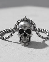 Artisan silver skull pendant with a bead chain, showcasing its oxidized details on a bright, textured surface.