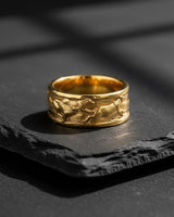 14K gold vermeil wolf ring featuring dynamic running wolves relief design displayed on textured black stone background