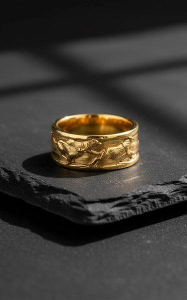 14K gold vermeil wolf ring featuring dynamic running wolves relief design displayed on textured black stone background