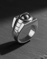 Polished sterling silver version of the Lantern Ring with a black central stone, displayed at an angle on a dark surface.