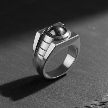 Polished sterling silver version of the Lantern Ring with a black central stone, displayed at an angle on a dark surface.