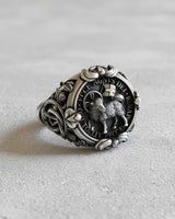 Angled view of the sterling silver Agnus Dei ring showcasing the intricate Chi-Rho symbol on the side band and ornate shoulder details.