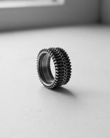 Handcrafted silver biomechanical ring with a smooth interior band, standing on a clean white surface to showcase its depth.
