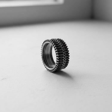 Handcrafted silver biomechanical ring with a smooth interior band, standing on a clean white surface to showcase its depth.