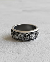 Side profile of the oxidized silver phoenix ring, displaying the continuous mythical bird design on a light gray stone.