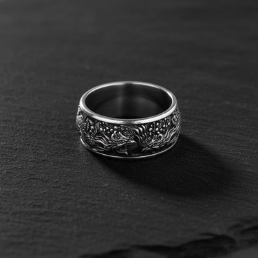 Silver Phoenix Ring with detailed Basan fire bird carving, shown from the front on a dark, textured slate surface.