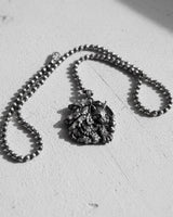 Silver lynx pendant on a ball chain, showcased on a textured white surface with artistic shadows from natural light.