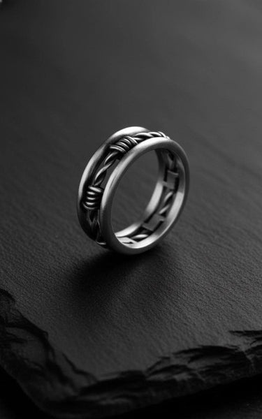 Close-up of the 925 sterling silver barbed wire ring, highlighting the oxidized finish and intricate details on a dark slate.
