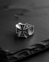 Angled shot of the Silver Maltese Cross Ring on a dark slate surface, highlighting its oxidized finish and solid band.