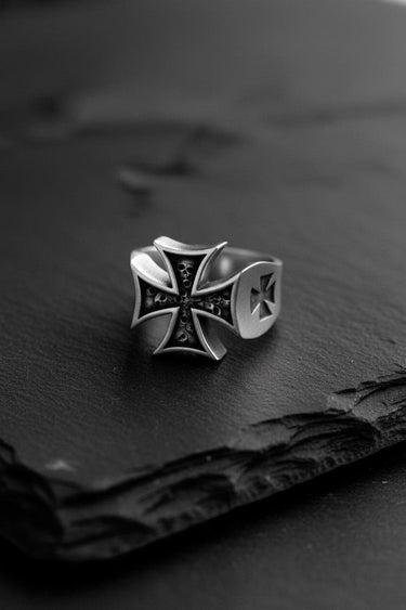 Angled shot of the Silver Maltese Cross Ring on a dark slate surface, highlighting its oxidized finish and solid band.