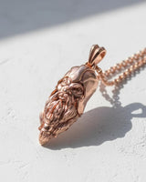 Rose gold Viking head pendant worn on a chain, showing its size and intricate design in natural side lighting.