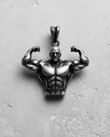 Oxidized 925 sterling silver bodybuilder pendant in a double biceps pose, shown from the front on a textured surface.