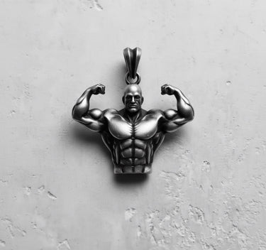 Oxidized 925 sterling silver bodybuilder pendant in a double biceps pose, shown from the front on a textured surface.