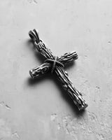 Oxidized Silver Wood Cross Pendant with detailed rope and grain texture, shown on a light grey concrete background.