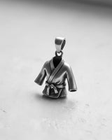 Sterling silver martial arts uniform pendant in a black and white photo showing the side angle and depth of the Gi on a clean surface.