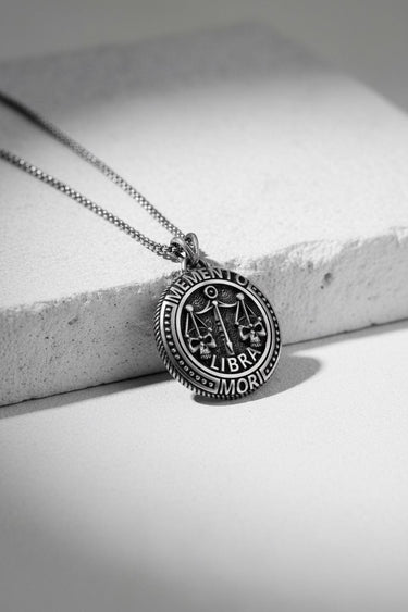 Oxidized Silver Libra Skull Pendant with Memento Mori text, showing detailed skull scales resting on a white surface.