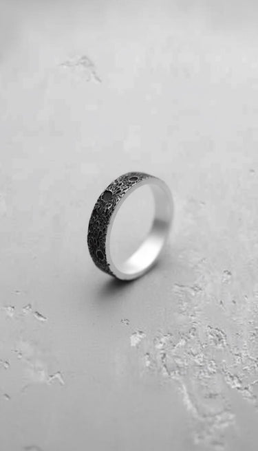 Silver moon ring with oxidized crater texture, showing the contrast with its polished sterling silver interior and edges.