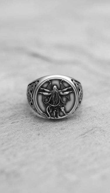 Silver Cthulhu ring with detailed tentacles and wings, showcasing the intricate handcrafted design on a grey stone surface.