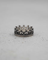 925 sterling silver crown ring with an oxidized finish and fleur-de-lis details, shown on a light grey textured surface.